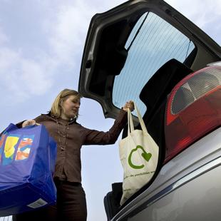 Woman loading reusable shopping bags into a car boot