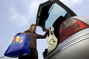 Woman loading reusable shopping bags into a car boot